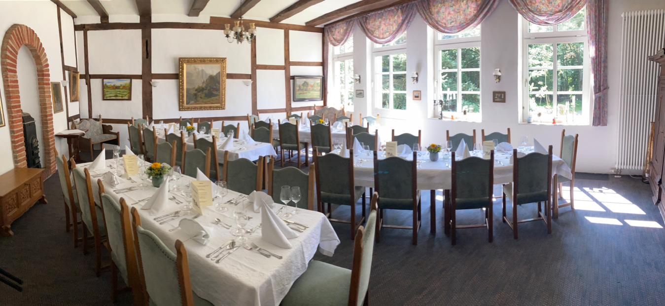 Fachwerkstube mit gedeckter Tafel, grünen Stühlen und großer Fensterfront